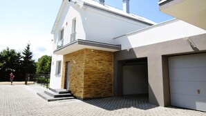 Ein modernes, zweistöckiges Haus mit Garage, einer kleinen Außentreppe und einem gepflasterten Auffahrt.