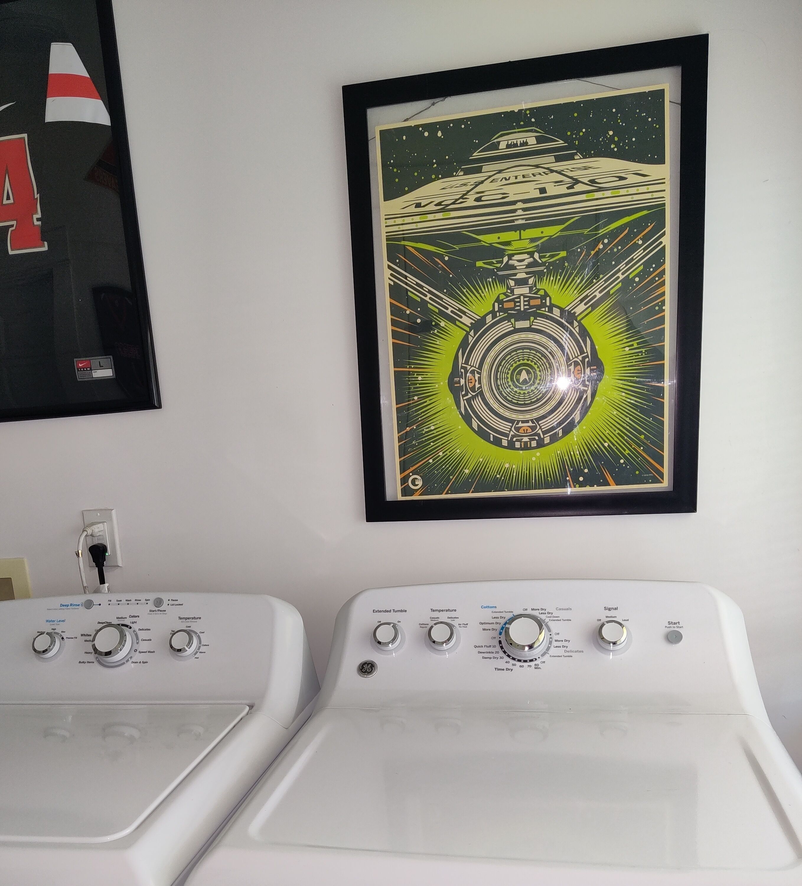Ein Waschbereich mit zwei Waschmaschinen mit Frontlader und einem gerahmten Kunstwerk, das ein UFO zeigt.