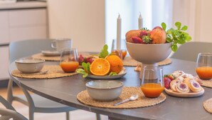A breakfast table with a bowl of fruit, orange juice, and pastries.