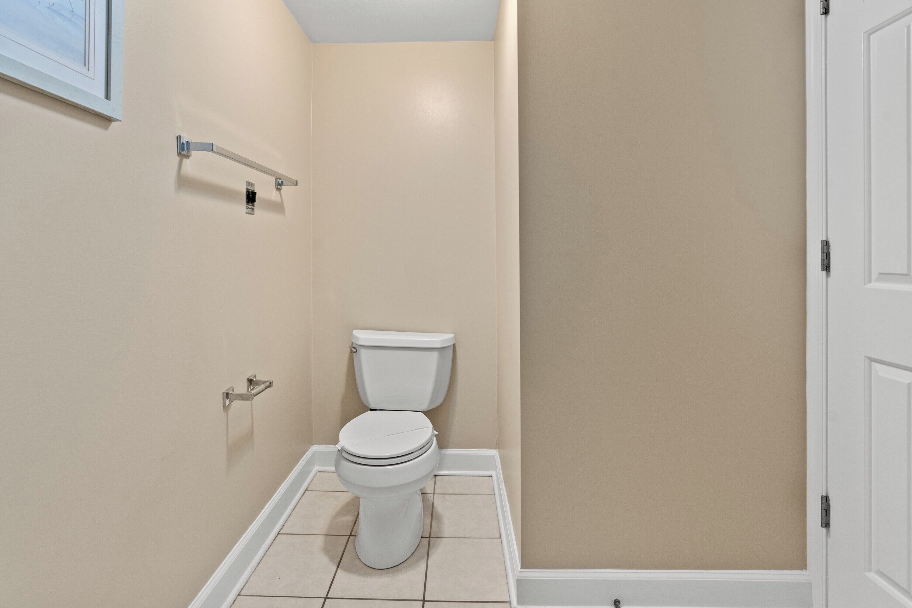 A small, clean bathroom with a toilet, a towel rack, and a framed picture on the wall.