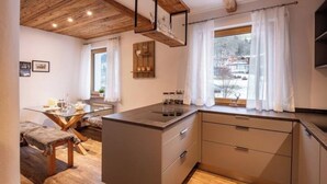 Una cocina moderna con una isla central, vigas de madera en el techo y vistas a un paisaje nevado por la ventana.