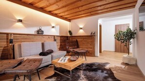 Una sala de estar acogedora con techo de madera, un sofá, una mesa de centro y un tapete de cuero.
