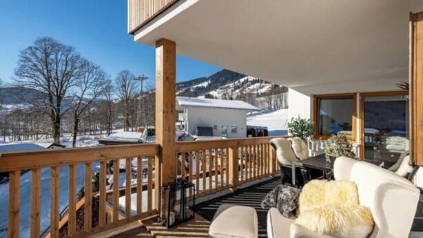 Una terraza de madera con vistas a montañas nevadas y árboles.