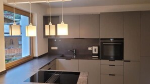 Una cocina moderna con estufa integrada, un lavaplatos y lámparas colgantes.