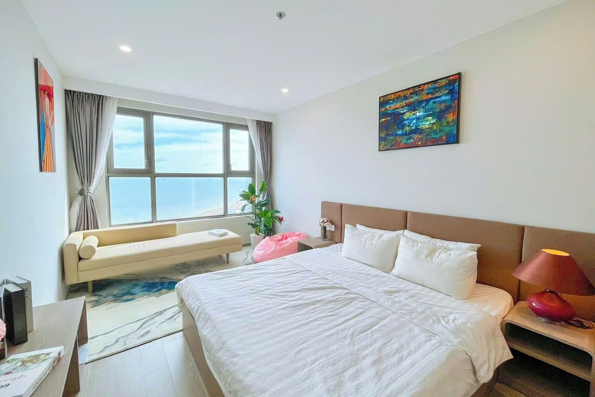 Una habitación de hotel moderna con una cama grande, un sofá, un escritorio y una ventana con vistas.