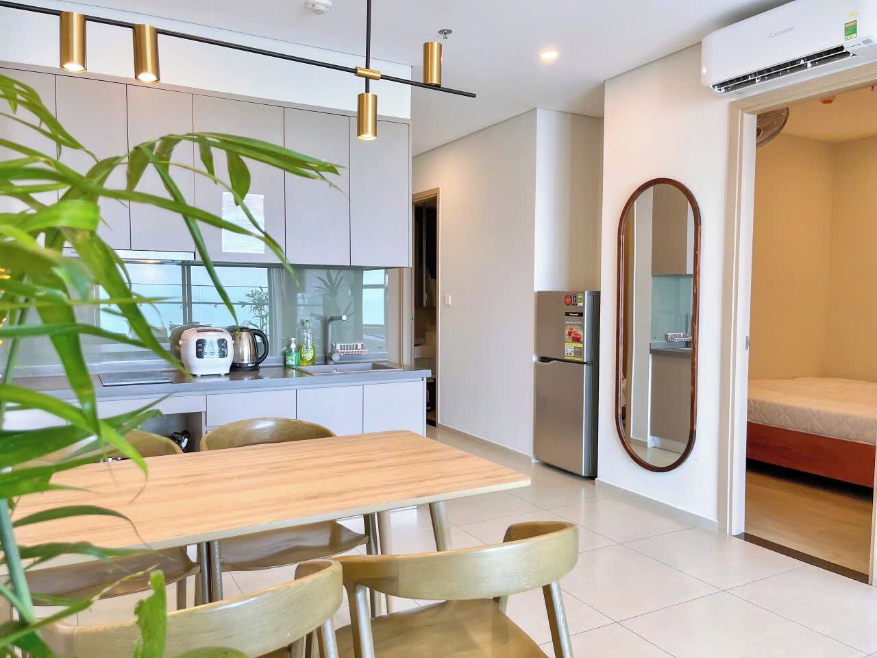 A modern kitchen with a dining table and chairs, a refrigerator, and a large mirror.