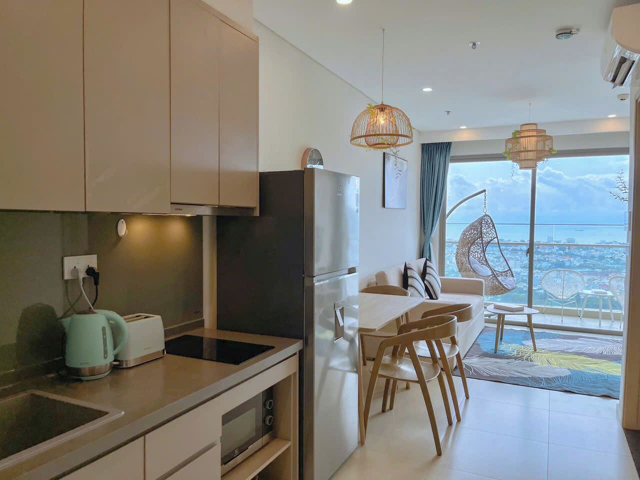 Une cuisine moderne avec un coin repas, une grande fenêtre offrant une belle vue et un balcon aménagé avec du mobilier d’extérieur.