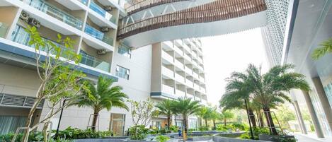 A modern multi-story building with balconies, outdoor seating areas, and greenery.