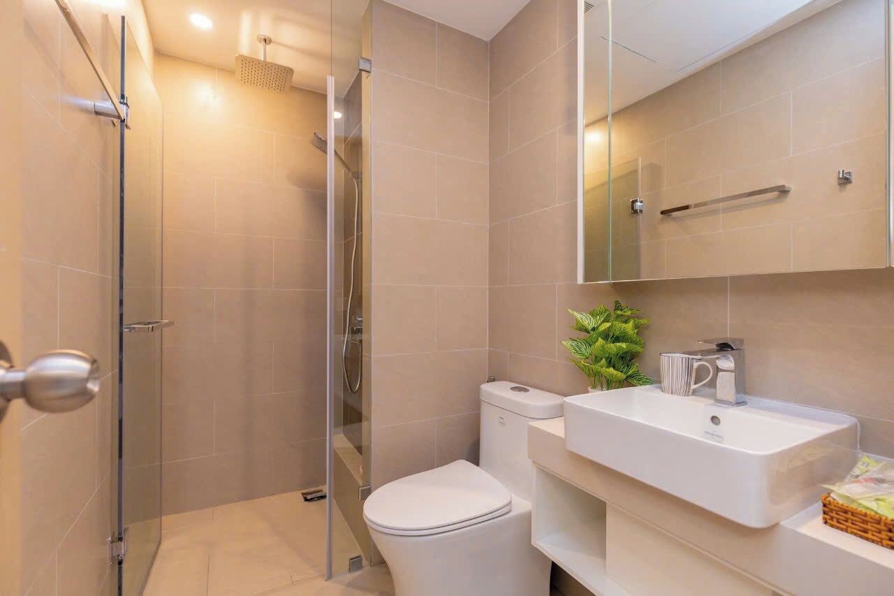 A modern bathroom with a glass shower enclosure, a white toilet, and a sink with a mirror above it.