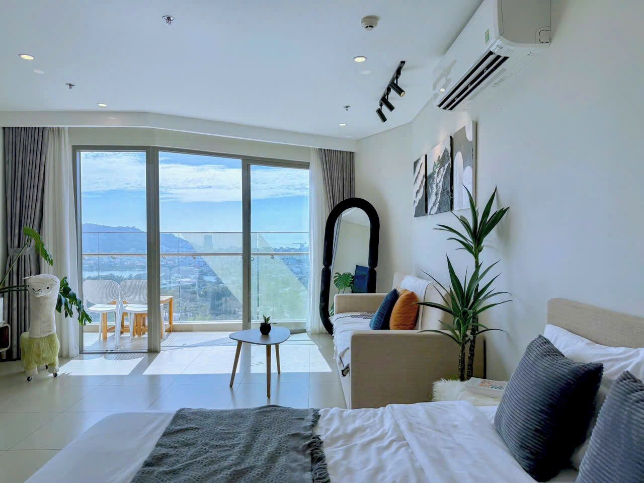 Una camera d'albergo moderna con un letto grande, un divano, un tavolino e un balcone vista città.