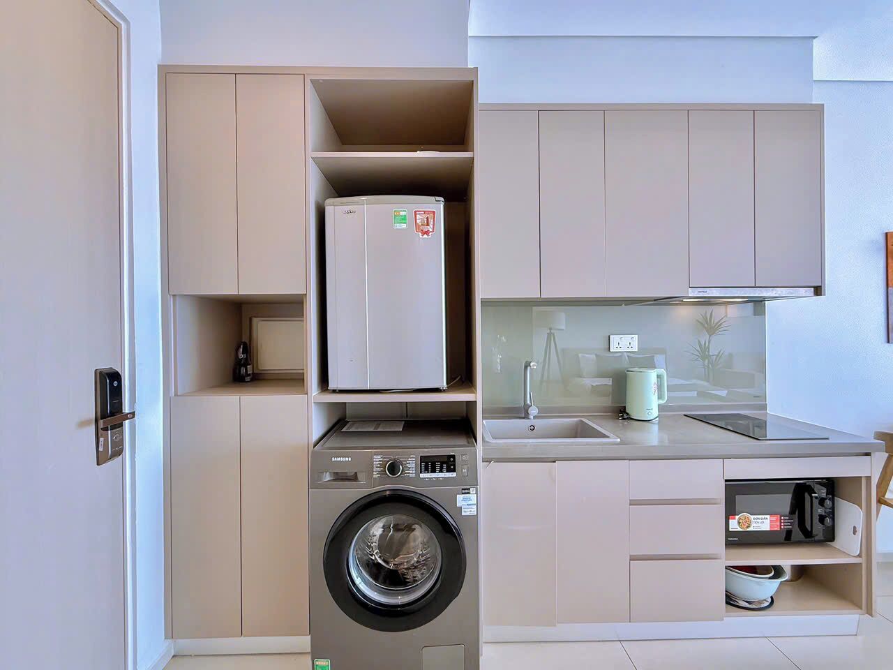 A compact kitchen with a washing machine, a microwave, and a small sink.