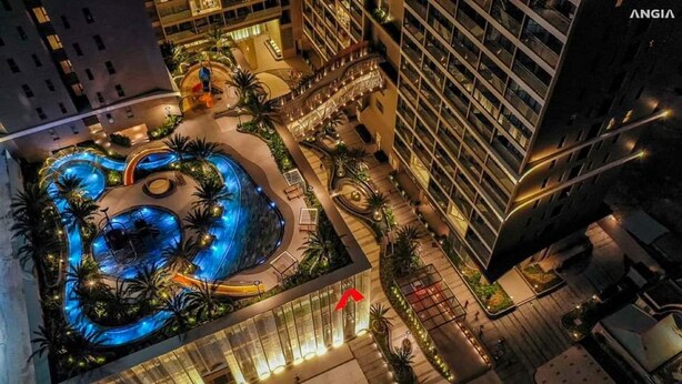 Un hotel con una amplia piscina cubierta rodeada de palmeras y una fuente central.