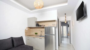 Una cocina compacta con refrigerador de acero inoxidable, encimera de madera y horno empotrado.