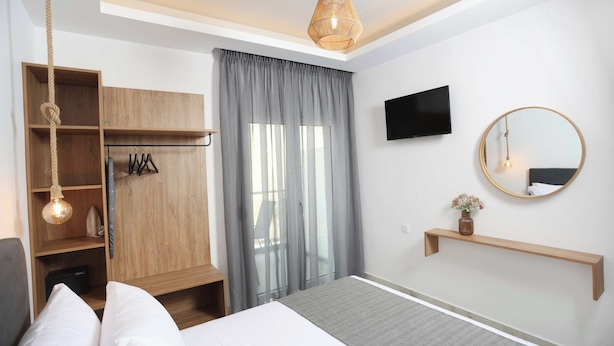 Una habitación de hotel moderna con una cama, un armario de madera, un televisor, un espejo y una lámpara colgante.