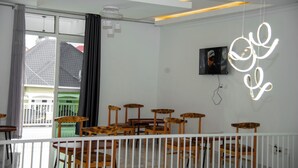A room with a dining area featuring wooden chairs and tables, a white railing, and a large window with curtains. - THE TREKKER'S REST LODGE (Cyuve)