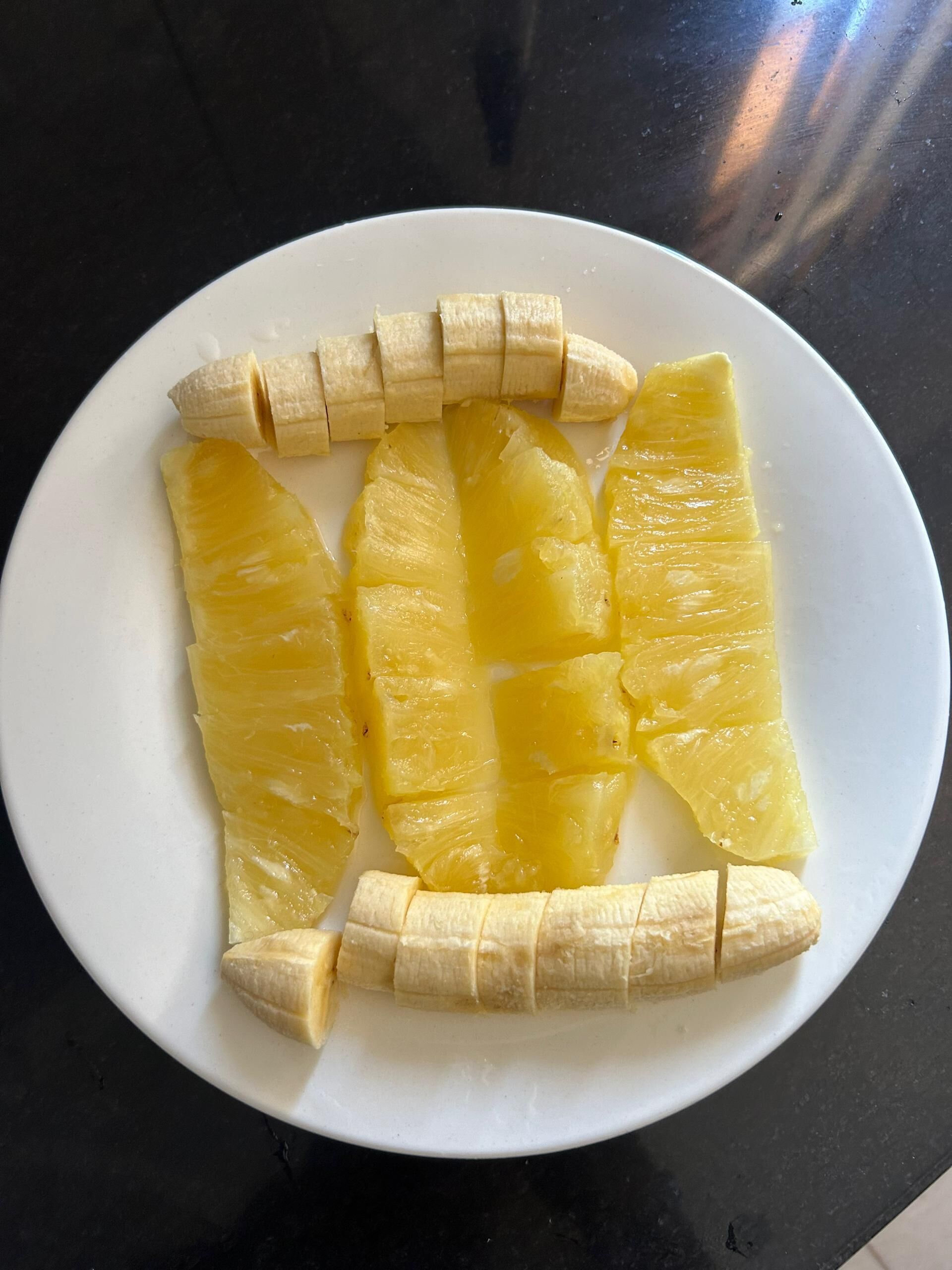 Un plato blanco con trozos de piña y plátano.