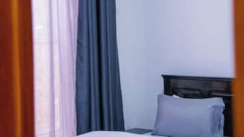 Un dormitorio con cama, mesita de noche y ventana con cortinas.