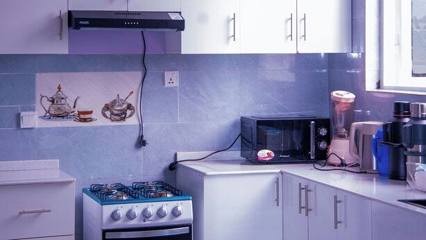 Een moderne keuken met witte kasten, een gasfornuis, een magnetron en een broodrooster.