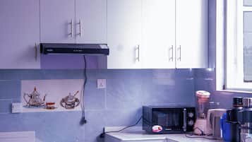 A modern kitchen with white cabinets, a gas stove, a microwave, and a toaster.