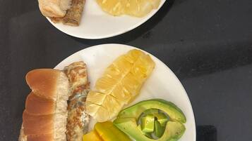Two plates with fried fish, mango, and avocado.