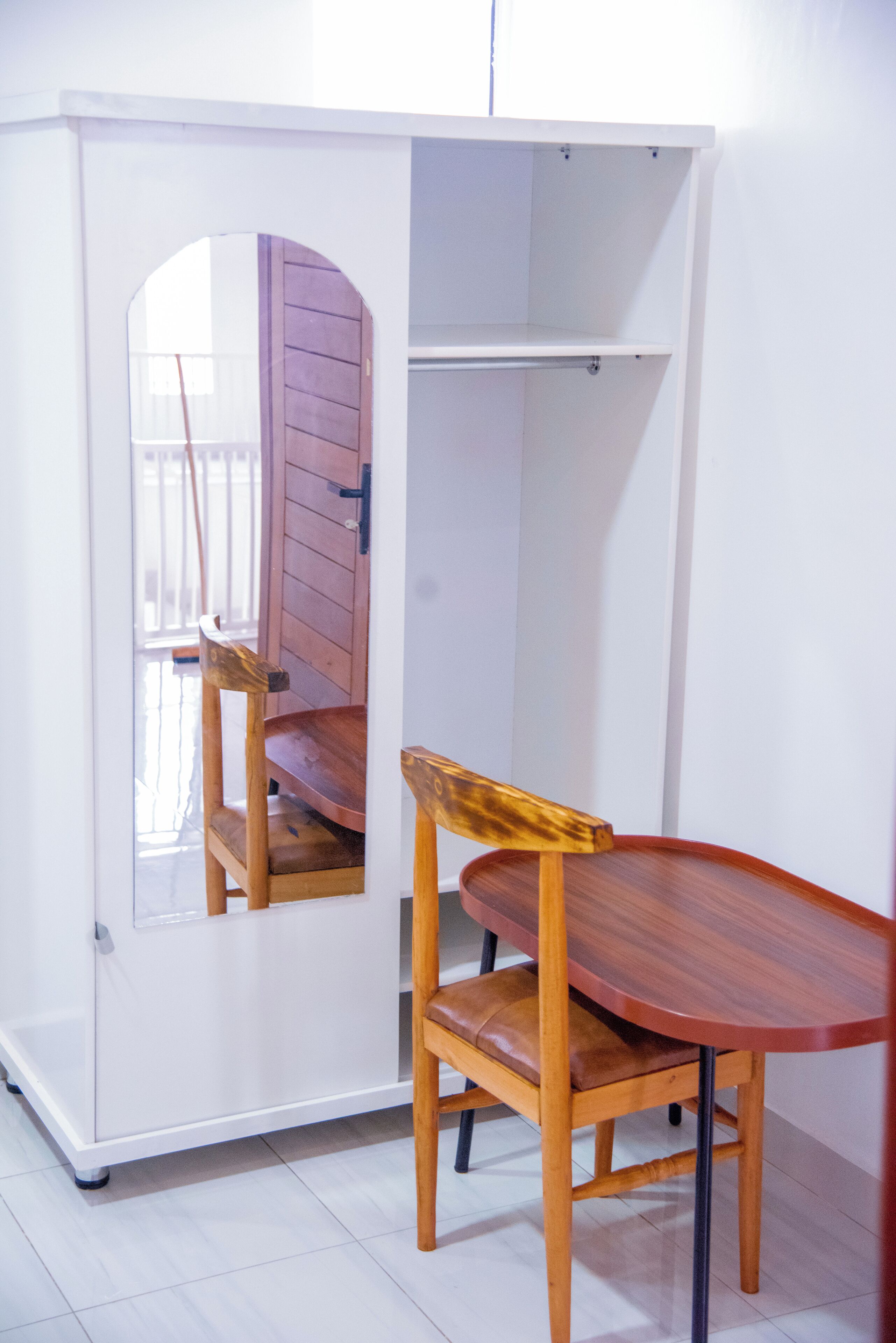 A room with a white cabinet, a wooden chair, and a table.