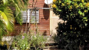 A wooden house with a satellite dish, surrounded by lush greenery and flowering plants. - Quiet, air-conditioned bed and breakfast 200 m from Le Diamant beach. (Le Diamant)