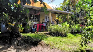 A yellow house with a porch, surrounded by lush greenery and a hammock. - Quiet, air-conditioned bed and breakfast 200 m from Le Diamant beach. (Le Diamant)