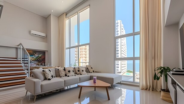 A modern living room with a large sectional sofa, a wooden coffee table, and a staircase.