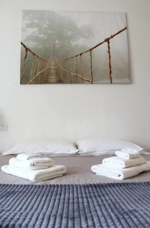 A bedroom with a bed, white pillows, and neatly folded towels.