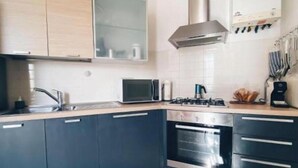 Una cocina moderna con armarios oscuros, una campana extractora de acero inoxidable y un microondas.