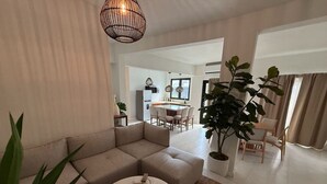 A modern living room with a sectional sofa, a round coffee table, and a dining area with a table and chairs.