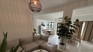 A modern living room with a sectional sofa, a round coffee table, and a dining area with a table and chairs.