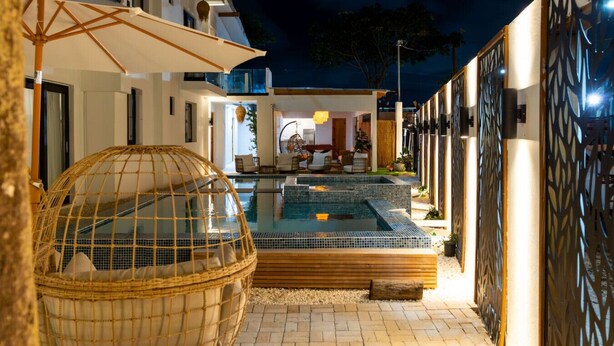 A pool area with a spherical seating structure, a covered seating area, and a pool with a tiled edge.