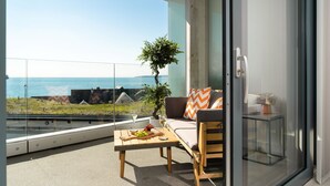 A balcony with a table, seating, and a view of the sea. - 24 The Liner sits so close to the cove that the fresh sea breeze flows in through the windows. (Falmouth)