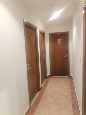 Un pasillo con tres puertas de madera, cada una con una placa con número.