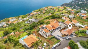 An aerial view of a coastal residential area with houses, roads, and a marked location.