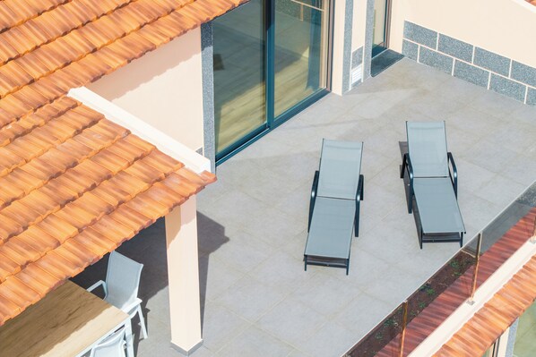 A rooftop terrace with two sun loungers, a table, and chairs. - Sunset House II (Arco da Calheta)