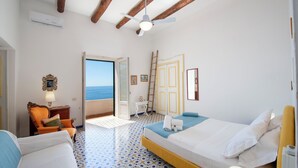 Ein Hotelzimmer mit Bett, Stuhl, Schreibtisch und Meerblick.