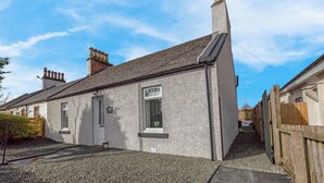 A single-story house with a grey exterior, a chimney, and a small window. - Arran Cottage Spacious 4-Bedroom House (Coatbridge)