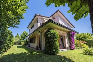 Une maison à deux étages dotée d’un porche abrité, d’une pelouse bien entretenue et entourée de verdure.