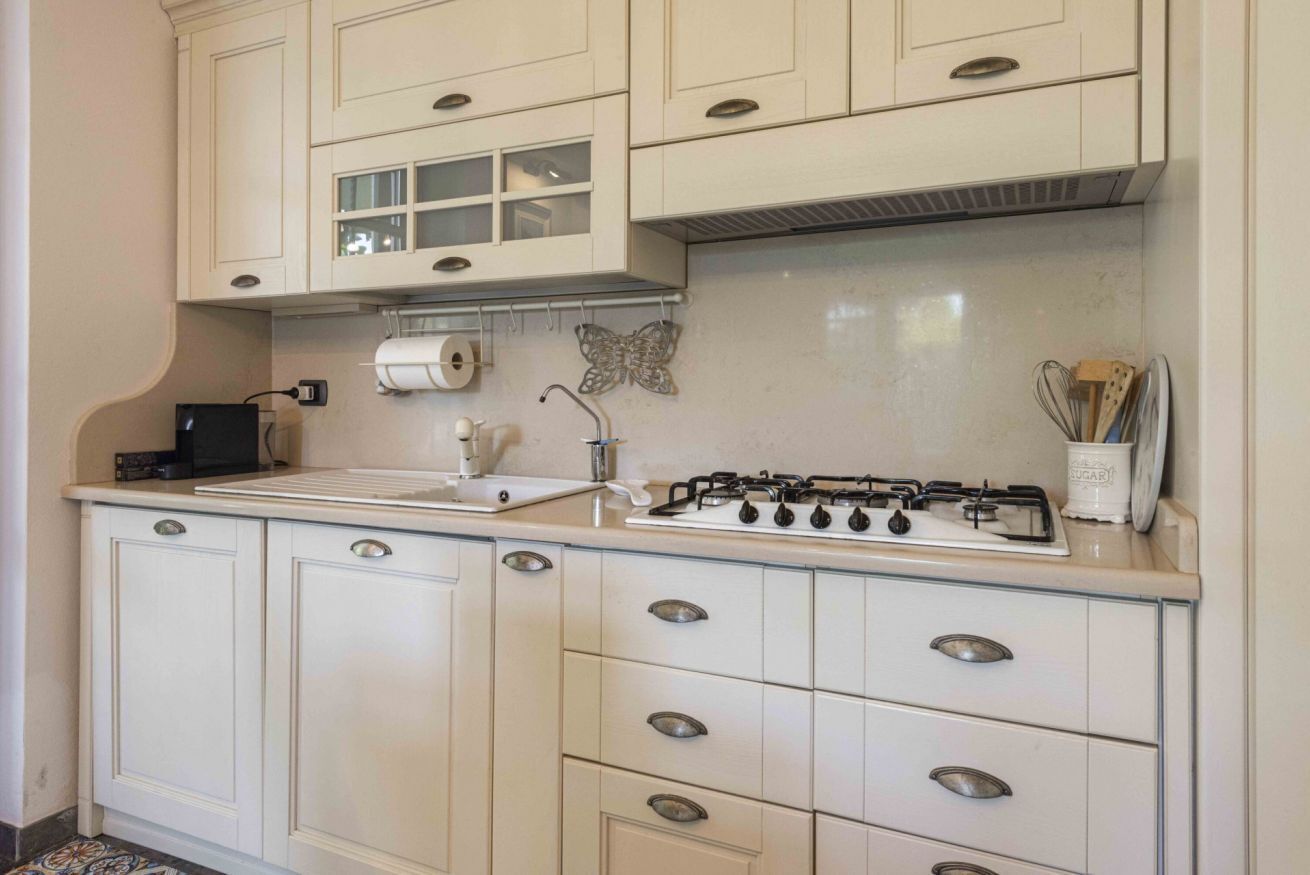 A kitchen with white cabinets, a gas stove, a sink, and a decorative butterfly.