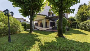 A house with a hammock, trees, and a lamp post. - Villa Federica by MMega (Forte dei Marmi)