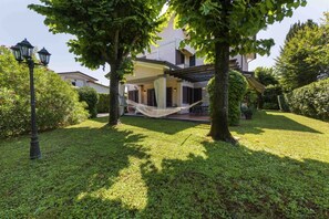 A house with a hammock, trees, and a lamp post.