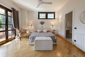 Une chambre à coucher comprenant un lit, une chaise, une fenêtre, un ventilateur de plafond et un radiateur.