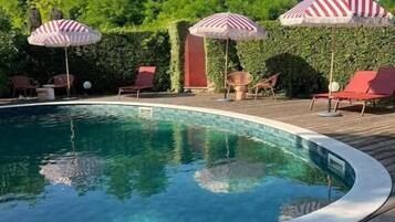 Una piscina al aire libre, sombrillas, tumbonas