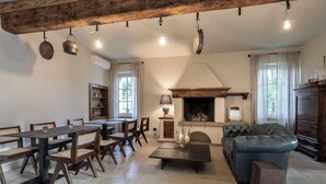 A cozy living room with a fireplace, a dining area with wooden furniture, and a leather sofa.