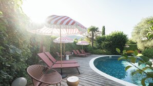 A poolside area with lounge chairs, striped umbrellas, and a wooden deck.