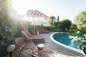 Una piscina al aire libre, sombrillas, sillones reclinables de piscina
