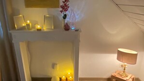 A cozy room with a fireplace, candles, a lamp, and a fur rug on the floor. - To complete (Burgbrohl)