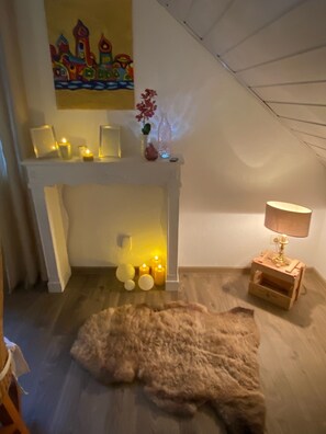 A cozy room with a fireplace, candles, a lamp, and a fur rug on the floor. - To complete (Burgbrohl)